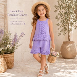 May include: A young person wearing a lavender knit top and shorts set, complemented by a straw hat and white sandals. The outfit features a detailed leaf pattern. The image includes the text "Sweet Knit Timeless Charm" and "Handmade with Love for Your Little One".