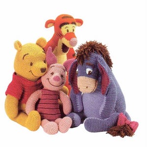 May include: A group of four crocheted plush toys featuring characters from Winnie the Pooh. The toys include Winnie the Pooh in yellow, Piglet in pink, Tigger in orange, and Eeyore in blue. Each toy has distinct features.
