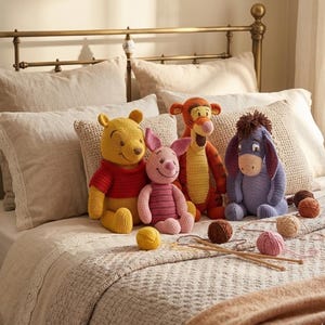 May include: A collection of handmade crochet Winnie the Pooh characters, including Winnie, Piglet, Tigger, and Eeyore, are arranged on a bed with yarn and knitting needles. The toys are in bright colors, with yarn balls and knitting needles.