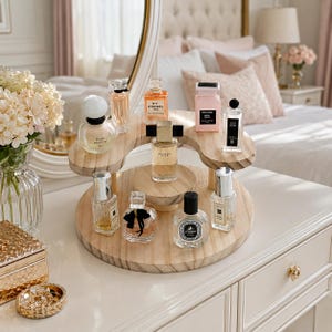May include: A tiered wooden display stand holding various glass perfume bottles of different shapes and sizes. The stand features a circular base and a curved upper shelf, showcasing brands like Chanel, Tom Ford, Dior, and Jo Malone on a vanity.