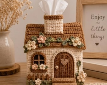 Puede incluir: Una funda de ganchillo para caja de pañuelos con forma de casa, techo marrón, paredes crema y chimenea. Incluye una puerta arqueada marrón con un botón en forma de corazón, una ventana con jardineras y enredaderas verdes con flores.