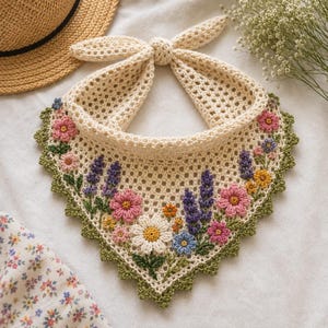 May include: A cream-colored triangular crochet bandana featuring an intricate floral pattern with lavender, pink, yellow, and blue flowers. The edges are finished with a green scalloped border, and the top includes two long ties for fastening.