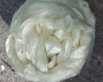 May include: A close-up of a large clump of white silk fibers. The fibers are soft and fluffy, and they are arranged in a loose, tangled mass.