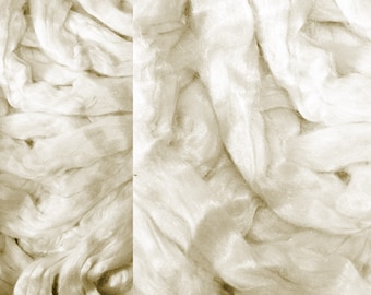 May include: A close-up of a pile of white and cream coloured silk fabric. The fabric is soft and luxurious, with a subtle sheen.