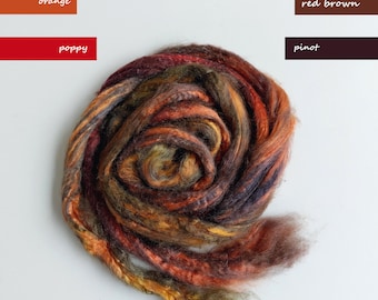 Op de afbeelding: Een close-up van een bundel kleurrijk garen in tinten oranje, rood, bruin en groen. Het garen is in een cirkelvorm gerangschikt, met de uiteinden van het garen die uit het midden steken.
