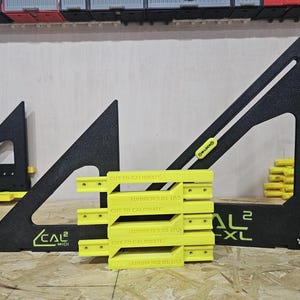 May include: A black triangular layout square with a green scale marked up to 280 mm, labeled CAL2-XL, alongside a smaller black square labeled CAL2-MIDI. Five bright yellow rectangular blocks with the text CUT TO CALIBRATE are stacked centrally.