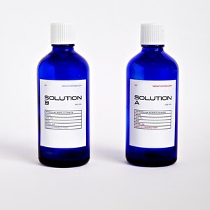 Pode incluir: Duas garrafas de vidro azul cobalto com tampas de rosca brancas. Cada garrafa tem um r&oacute;tulo branco com texto preto que diz "SOLUTION" e o nome qu&iacute;mico. As garrafas t&ecirc;m 100 ml cada.