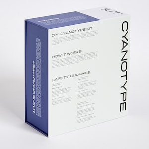Pode incluir: Uma caixa de kit de cianotipia com um design azul e branco. A caixa apresenta o texto "DIY CYANOTYPE KIT" e "CYANOTYPE" em preto. A caixa tamb&eacute;m inclui instru&ccedil;&otilde;es e diretrizes de seguran&ccedil;a.