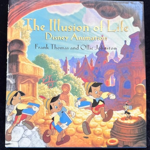 May include: A hardback book titled The Illusion of Life Disney Animation by Frank Thomas and Ollie Johnston. The cover features a colourful illustration of Pinocchio in three different poses carrying blue books, with Jiminy Cricket nearby.