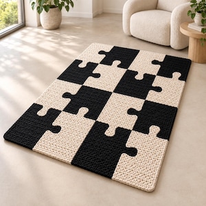 Puede incluir: Una alfombra rectangular con un patrón repetitivo de piezas de rompecabezas entrelazadas. La alfombra está confeccionada con un material tejido y texturizado, con secciones alternas de color negro sólido y crema que encajan entre sí.