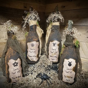 Op de afbeelding: Vier decoratieve flessen met etiketten waarop "Lanta Spell" staat en een jaar en een naam voor de spreuk worden vermeld. De flessen zijn gewikkeld in jute en mos en hebben een rustieke, vintage uitstraling.