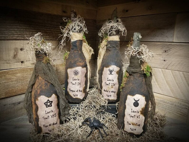Op de afbeelding: Vier decoratieve flessen met etiketten waarop "Lanta Spell" staat en een jaar en een naam voor de spreuk worden vermeld. De flessen zijn gewikkeld in jute en mos en hebben een rustieke, vintage uitstraling.