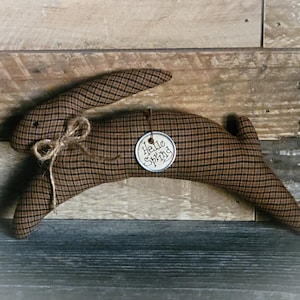 May include: A brown and tan plaid bunny rabbit with a burlap bow and a tag that says "Hello Spring".
