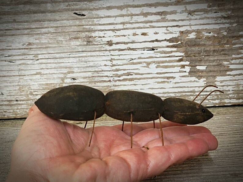 Pu&ograve; includere: Una formica di stoffa marrone fatta a mano con gambe di filo metallico. La formica &egrave; seduta sulla mano di una persona.