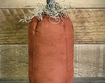 May include: A tall, cylindrical fabric pumpkin in a muted burnt orange colour. The top features a textured, natural-looking wooden stem surrounded by a cluster of light-coloured, wispy dried moss fibres that sit atop the fabric body.