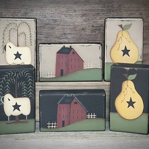 May include: Six wooden blocks with painted scenes. The blocks feature a red barn, a weeping willow tree, a sheep, and a pear. Each block has a black star painted on it.
