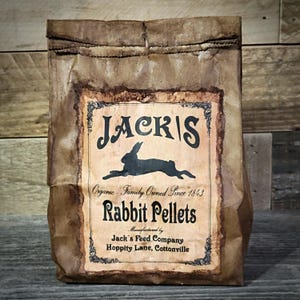 May include: A brown paper bag with a label that reads "JACK'S Organic Family Owned Since 1843 Rabbit Pellets Manufactured by Jack's Feed Company Hoppity Lane, Cottonville". The label features a black silhouette of a rabbit.