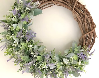 May include: A grapevine wreath decorated with artificial lavender and eucalyptus sprigs.