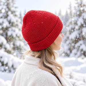 Può includere: Un berretto in maglia rosso vivace con un bordo spesso ripiegato e una consistenza a coste. Il cappello è realizzato con un classico motivo a maglia rasata e presenta una corona arrotondata, offrendo una vestibilità aderente.