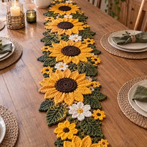 May include: A long, rectangular crochet table runner featuring a repeating pattern of large yellow sunflowers with dark brown centers, interspersed with smaller white daisy-like flowers and textured dark green leaves, all connected in a floral design.