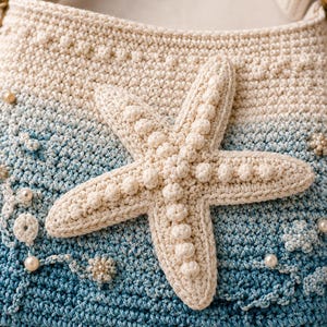 May include: A crochet shoulder bag featuring an ombre color gradient from cream at the top to deep blue at the bottom. The bag is decorated with a large, three-dimensional cream-colored starfish, small crocheted floral accents, and white beads.