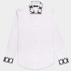 May include: A long-sleeved white button-down shirt featuring a pointed collar and cuffs decorated with a black geometric cross-hatch pattern. The shirt has a central vertical row of white buttons and a curved hemline at the bottom of the garment.