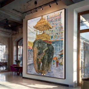 Op de afbeelding: Een grote verticale wandkunstprint met een aquarel van een grijze olifant die een gouden ceremoniële structuur op zijn rug draagt. De olifant is versierd met een kleurrijke kralenketting en staat voor een hoge, rijk versierde tempeltoren.