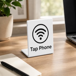 May include: A white L-shaped acrylic sign featuring a black circular Wi-Fi icon and the text Tap Phone printed in black. The sign stands upright on a flat surface, providing a clear visual indicator for contactless mobile device interaction.