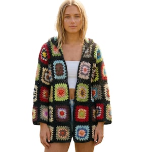 May include: A long-sleeved hooded cardigan constructed from a patchwork of multicolored crochet granny squares. The squares feature various color combinations including red, yellow, green, blue, and pink, all bordered by black yarn throughout the garment.