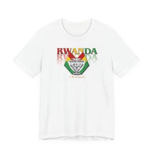Può includere: Una t-shirt bianca a maniche corte con la parola RWANDA in lettere rosse, gialle e verdi. Sotto il testo si trova un emblema a forma di scudo con la scritta REPUBLIQUE RWANDAISE LIBERTE-COOPERATION-PROGRES e un piccolo logo Rwanda in corsivo.