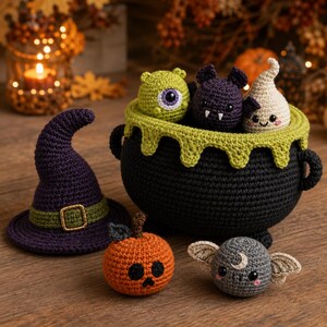 May include: A collection of crocheted items including a black cauldron with green trim, a purple witch hat with a green band, an orange pumpkin, a gray bat with a crescent moon, a green cyclops, a purple bat, and a cream-colored ghost.