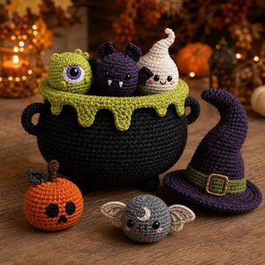 May include: A black crocheted cauldron with a green drip rim containing a green cyclops, a purple bat, and a white ghost. Beside it sits an orange pumpkin, a grey moth with a crescent moon, and a purple witch hat with a green band and gold buckle.
