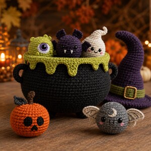 May include: A black crocheted cauldron with a green dripping rim containing a green cyclops, a purple bat, and a white ghost. Beside it sits an orange pumpkin with a skull face, a grey moth with a moon, and a purple witch hat with a green band.