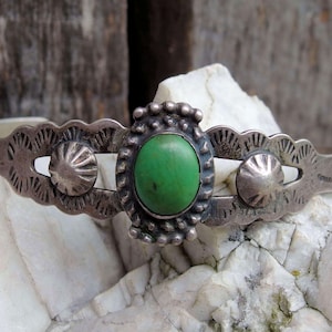 以下が含まれることがあります： 緑色のターコイズストーンと複雑な銀の模様が施された銀のブレスレット