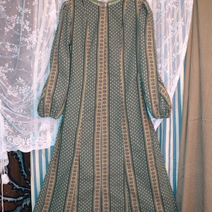 May include: A long-sleeved sage green dress featuring a repeating white floral pattern and vertical striped panels in shades of brown, yellow, and green. The garment has a round neckline, a fitted bodice, and a flared skirt with long sleeves.