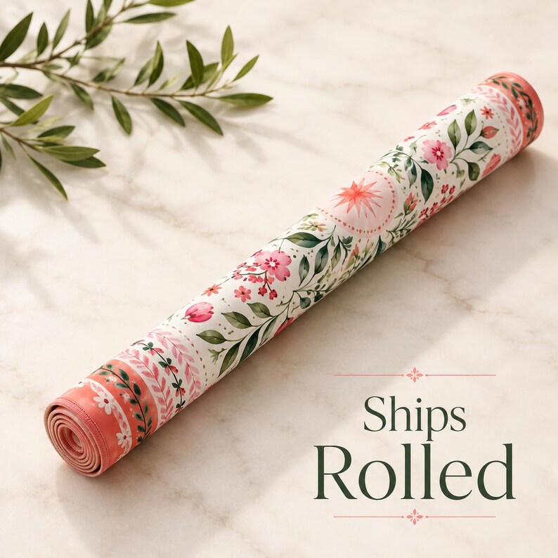 May include: A cylindrical mat rolled tightly, featuring a white background with a repeating pattern of pink flowers, green leaves, and small starburst motifs. The edges of the mat display a decorative border with pink and green botanical elements.