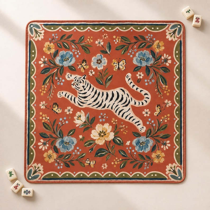 May include: A square mat with a rust-orange background featuring a central white tiger with black stripes in a leaping pose. The design includes blue and yellow flowers, green leaves, and small butterflies, all framed by a scalloped green border.