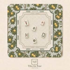 May include: A square Mahjong game mat with a light green and beige floral design. The mat features a central playing area and is surrounded by a border with lemon tree illustrations. Several Mahjong tiles are scattered on the mat. The mat has the text "Tiles for Four".