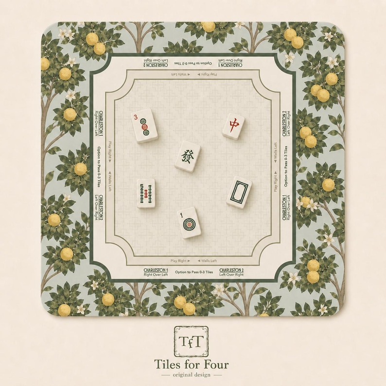 May include: A square Mahjong game mat with a light green and beige floral design. The mat features a central playing area and is surrounded by a border with lemon tree illustrations. Several Mahjong tiles are scattered on the mat. The mat has the text "Tiles for Four".