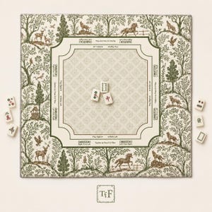 May include: A square mahjong mat featuring a cream-colored center with a repeating cross pattern and green text instructions. The border displays a green and cream forest scene with animals. Three mahjong tiles sit in the center, with six more tiles placed outside the mat.