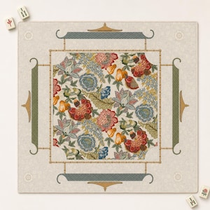May include: A square mahjong mat featuring a central panel with a dense floral pattern in red, blue, green, and yellow on a cream background. The border is framed by a bamboo-style design with four green decorative accents and small tiles.