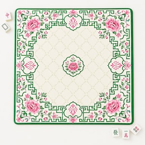 May include: A square mahjong mat featuring a cream-colored center with a subtle diamond pattern and a central pink floral motif. The border displays a green geometric fretwork design accented with pink peonies, green leaves, and small pink flower buds.