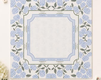 Può includere: Un tappetino da Mahjong quadrato con centro bianco, bordi azzurri e testo che include Charleston 1, Charleston 2, Walls Left e Play Right. Il bordo è decorato con un motivo ripetitivo di fiori di ortensia color azzurro.