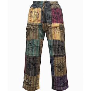 May include: Patchwork cargo pants featuring a multi-colored striped pattern in shades of yellow, teal, red, and dark purple. The pants include a drawstring waistband, two side cargo pockets, and a repeating black floral print across the panels.