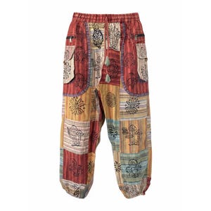 Puede incluir: Pantalones de patchwork con un diseño multicolor que incluye paneles rojos, amarillos y azules. La tela muestra gráficos impresos en negro de setas y patrones florales circulares. Estos pantalones incluyen una cintura elástica.