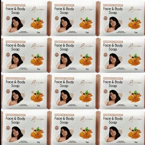 May include: Twelve identical rectangular bars of Byenblan Turmeric Face & Body Soap in white packaging. Each label features a photograph of a person, a graphic of turmeric roots with a wooden scoop, the text 7oz, and the claim 7 Days Results.