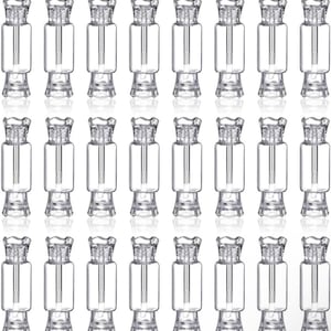 May include: A collection of twenty-four clear, empty plastic containers shaped like wrapped candies. Each small vessel features a cylindrical body, a screw-top cap with a decorative fluted edge, and an internal applicator wand attached to the lid.