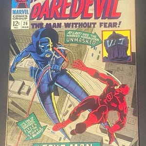 May include: A vintage Marvel comic book titled Here Comes Daredevil number 26, featuring a cover illustration of Daredevil in a red suit fighting Stilt-Man in a blue suit above a city. The text includes The Man Without Fear and Stilt-Man Strikes Again.