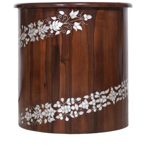 K&ouml;nnte beinhalten: Ein zylindrischer Beistelltisch aus Holz mit einer glatten, dunkelbraunen Oberfl&auml;che. Das &Auml;u&szlig;ere ist mit zwei diagonalen B&auml;ndern aus wei&szlig;er Blumenintarsie verziert, die komplizierte Blatt- und Blumenmuster auf der gew&ouml;lbten Fl&auml;che zeigen.