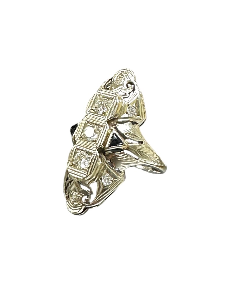 Pu&ograve; includere: Un anello d'oro con un design unico che presenta un gruppo di piccoli diamanti e una pietra nera pi&ugrave; grande al centro.